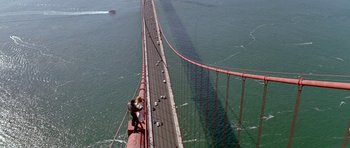 Movie still from “A View to a Kill” (1985), directed by John Glen – Two people standing on the side of a bridge over the water; Extreme Wide shot, High angle