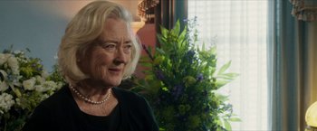 Movie still from “A Walk in the Woods” (2015), directed by Ken Kwapis – An older woman wearing a black shirt and pearl necklace in front of a flower arrangement; Close Up shot, Over the shoulder angle