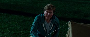 Movie still from “A Walk in the Woods” (2015), directed by Ken Kwapis – An older man sitting in the grass holding a fishing rod; Medium shot, Low angle