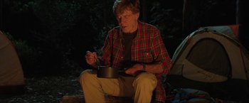 Movie still from “A Walk in the Woods” (2015), directed by Ken Kwapis – An older man sitting on the ground in front of a pot; Medium shot, Low angle