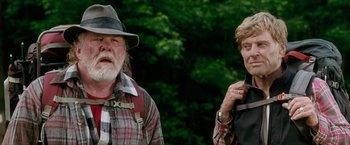 Movie still from “A Walk in the Woods” (2015), directed by Ken Kwapis – A man and a woman standing next to each other in front of trees; Medium shot, Low angle