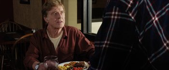 Movie still from “A Walk in the Woods” (2015), directed by Ken Kwapis – A man sitting in front of a plate of food; Medium shot, Over the shoulder angle