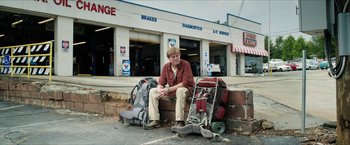 Movie still from “A Walk in the Woods” (2015), directed by Ken Kwapis – A man sitting on a wall next to a lot of luggage; Wide shot, Low angle