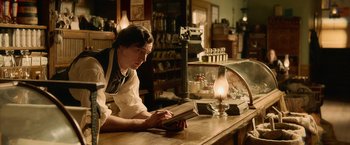Movie still from “Abraham Lincoln: Vampire Hunter” (2012), directed by Timur Bekmambetov – A person sitting at a table reading a book; Medium shot, Over the shoulder angle
