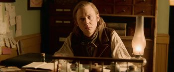 Movie still from “Abraham Lincoln: Vampire Hunter” (2012), directed by Timur Bekmambetov – A man sitting at a table in front of a bunch of drawers; Medium shot, Over the shoulder angle