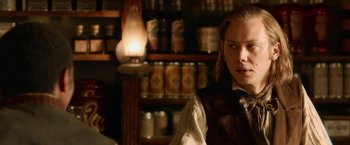 Movie still from “Abraham Lincoln: Vampire Hunter” (2012), directed by Timur Bekmambetov – A man in a vest standing in front of a lamp; Close Up shot, Over the shoulder angle