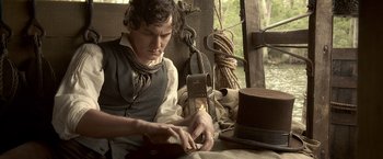 Movie still from “Abraham Lincoln: Vampire Hunter” (2012), directed by Timur Bekmambetov – A man in a vest and tie working on something on a table; Medium shot, High angle