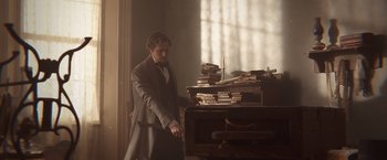 Movie still from “Abraham Lincoln: Vampire Hunter” (2012), directed by Timur Bekmambetov – A man standing next to a table with books on top of it; Medium shot, Low angle