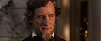 Movie still from “Abraham Lincoln: Vampire Hunter” (2012), directed by Timur Bekmambetov – A man with a long beard wearing a suit and tie; Close Up shot, Over the shoulder angle