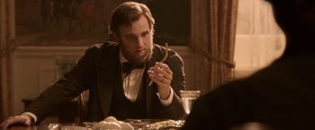 Movie still from “Abraham Lincoln: Vampire Hunter” (2012), directed by Timur Bekmambetov – A man sitting at a table with a cigarette in his mouth; Close Up shot, Over the shoulder angle