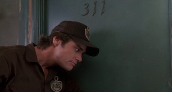 Movie still from “Ace Ventura: Pet Detective” (1994), directed by Tom Shadyac – A man wearing a baseball cap leaning up against a wall; Close Up shot, Low angle
