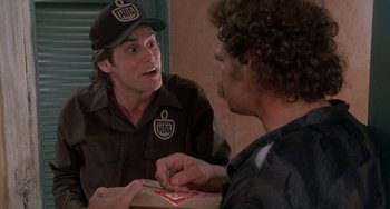 Movie still from “Ace Ventura: Pet Detective” (1994), directed by Tom Shadyac – A man is talking to another man while holding a box; Close Up shot, Over the shoulder angle