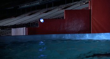 Movie still from “Ace Ventura: Pet Detective” (1994), directed by Tom Shadyac – A view of an indoor swimming pool at night time; Extreme Wide shot, High angle
