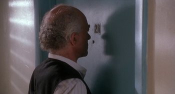 Movie still from “Ace Ventura: Pet Detective” (1994), directed by Tom Shadyac – A man standing in front of a wall with the number 2 1 on it; Close Up shot, Over the shoulder angle