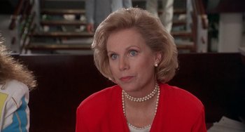 Movie still from “Ace Ventura: Pet Detective” (1994), directed by Tom Shadyac – An older woman wearing a red jacket and pearl necklace; Close Up shot, Low angle