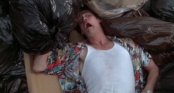 Movie still from “Ace Ventura: Pet Detective” (1994), directed by Tom Shadyac – A man laying on the ground with a bag of trash; Close Up shot, Overhead angle