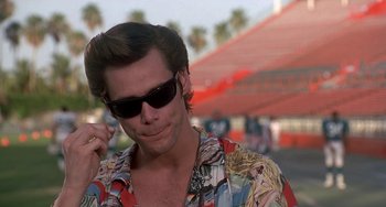 Movie still from “Ace Ventura: Pet Detective” (1994), directed by Tom Shadyac – A person wearing sunglasses and a hawaiian shirt; Close Up shot, Low angle