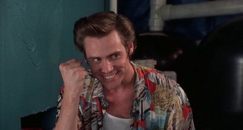 Movie still from “Ace Ventura: Pet Detective” (1994), directed by Tom Shadyac – A man in a colorful shirt smiling for the camera; Close Up shot, Low angle