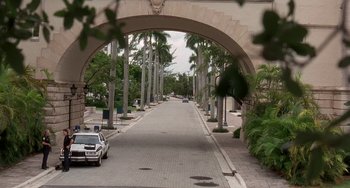 Movie still from “Ace Ventura: Pet Detective” (1994), directed by Tom Shadyac – A car is parked on the side of the road under an archway; Extreme Wide shot, High angle
