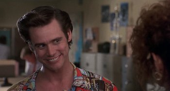 Movie still from “Ace Ventura: Pet Detective” (1994), directed by Tom Shadyac – A man with long brown hair wearing a hawaiian shirt; Close Up shot, Over the shoulder angle