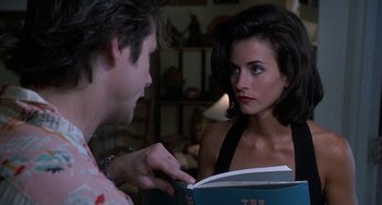 Movie still from “Ace Ventura: Pet Detective” (1994), directed by Tom Shadyac – A man and a woman looking at each other while holding a book; Close Up shot, Over the shoulder angle