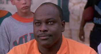 Movie still from “Ace Ventura: Pet Detective” (1994), directed by Tom Shadyac – A person wearing an orange shirt; Close Up shot, Low angle