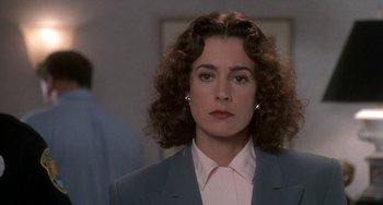 Movie still from “Ace Ventura: Pet Detective” (1994), directed by Tom Shadyac – A person with curly hair wearing a suit; Close Up shot, Over the shoulder angle