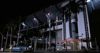 Movie still from “Ace Ventura: Pet Detective” (1994), directed by Tom Shadyac – A car parked in front of a building at night; Extreme Wide shot, Low angle