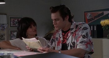 Movie still from “Ace Ventura: Pet Detective” (1994), directed by Tom Shadyac – A man and a woman sitting at a table; Medium shot, Over the shoulder angle