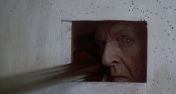 Movie still from “Ace Ventura: Pet Detective” (1994), directed by Tom Shadyac – An old man looking through a hole in the wall; Extreme Close Up shot, Low angle