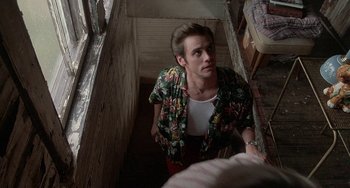 Movie still from “Ace Ventura: Pet Detective” (1994), directed by Tom Shadyac – A man in a hawaiian shirt is standing in a stairwell; Medium shot, Over the shoulder angle