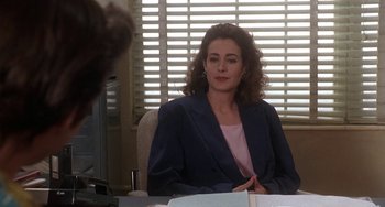 Movie still from “Ace Ventura: Pet Detective” (1994), directed by Tom Shadyac – A woman sitting at a desk in front of a computer monitor; Medium shot, Over the shoulder angle