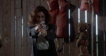 Movie still from “Ace Ventura: Pet Detective” (1994), directed by Tom Shadyac – A woman holding a gun in a room with stuffed animals; Medium shot, Low angle