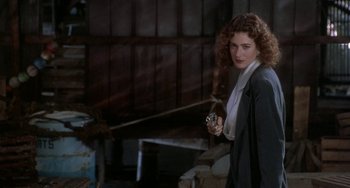 Movie still from “Ace Ventura: Pet Detective” (1994), directed by Tom Shadyac – A woman holding a camera in a dark room; Medium shot, Over the shoulder angle