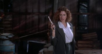 Movie still from “Ace Ventura: Pet Detective” (1994), directed by Tom Shadyac – A woman holding a cell phone while standing in front of a building; Medium shot, Low angle