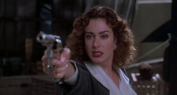 Movie still from “Ace Ventura: Pet Detective” (1994), directed by Tom Shadyac – A woman holding a gun pointed at the camera; Close Up shot, Low angle