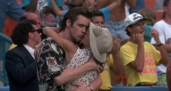 Movie still from “Ace Ventura: Pet Detective” (1994), directed by Tom Shadyac – A man and a woman kissing in front of a crowd; Close Up shot, Over the shoulder angle