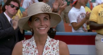Movie still from “Ace Ventura: Pet Detective” (1994), directed by Tom Shadyac – A woman wearing a hat and smiling for the camera; Close Up shot, Over the shoulder angle