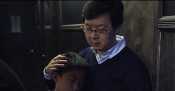 An older man is holding a young boy's head