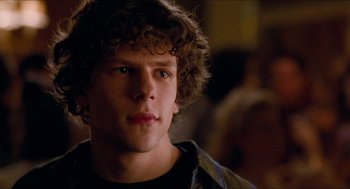 Movie still from “Adventureland” (2009), directed by Greg Mottola – A young man with curly brown hair and blue eyes stares ahead; Close Up shot, Over the shoulder angle