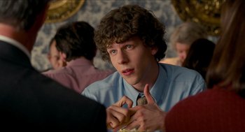 Movie still from “Adventureland” (2009), directed by Greg Mottola – A young man sitting at a table in front of a group of people; Close Up shot, Over the shoulder angle