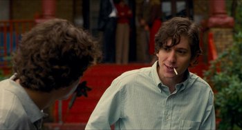 Movie still from “Adventureland” (2009), directed by Greg Mottola – A man smoking a cigarette in front of another man; Medium shot, Over the shoulder angle
