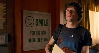 Movie still from “Adventureland” (2009), directed by Greg Mottola – A man standing in front of a smile sign; Medium shot, Over the shoulder angle