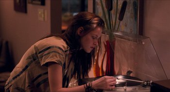 Movie still from “Adventureland” (2009), directed by Greg Mottola – A woman sitting at a table looking down at her cell phone; Medium shot, Over the shoulder angle