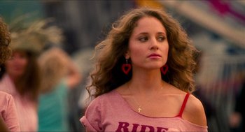 Movie still from “Adventureland” (2009), directed by Greg Mottola – A woman with long curly hair wearing a pink t - shirt; Close Up shot, Low angle
