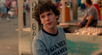 Movie still from “Adventureland” (2009), directed by Greg Mottola – A man with curly hair is sitting in front of a pole; Close Up shot, Over the shoulder angle