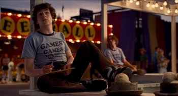Movie still from “Adventureland” (2009), directed by Greg Mottola – Two young men sitting on the ground in front of a marquee; Medium shot, Over the shoulder angle