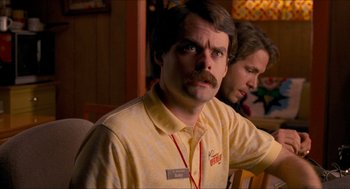 Movie still from “Adventureland” (2009), directed by Greg Mottola – A man in a yellow shirt is looking at the camera; Close Up shot, Over the shoulder angle