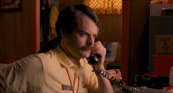 Movie still from “Adventureland” (2009), directed by Greg Mottola – A man talking on a phone while wearing a yellow shirt; Close Up shot, Low angle