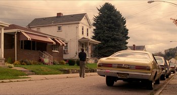 Movie still from “Adventureland” (2009), directed by Greg Mottola – A man standing on the side of the road next to a car; Wide shot, Over the shoulder angle